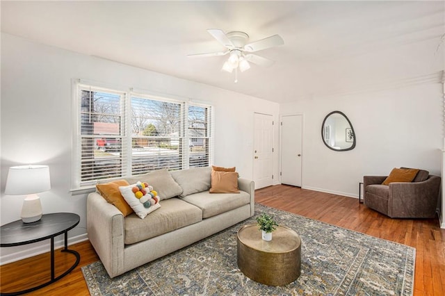 living room with ceiling fan, baseboards, and wood finished floors