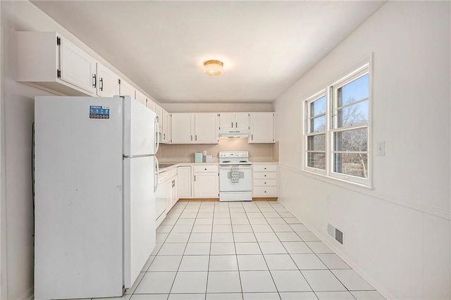 kitchen with visible vents, under cabinet range hood, light countertops, light tile patterned floors, and white appliances