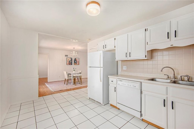 kitchen featuring a sink, tasteful backsplash, white appliances, white cabinets, and light countertops