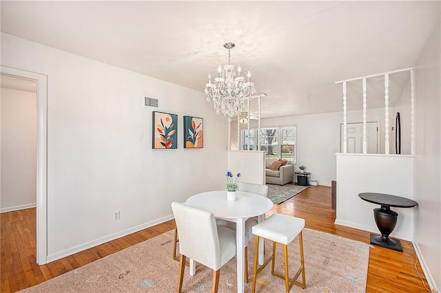 dining area with an inviting chandelier, wood finished floors, visible vents, and baseboards