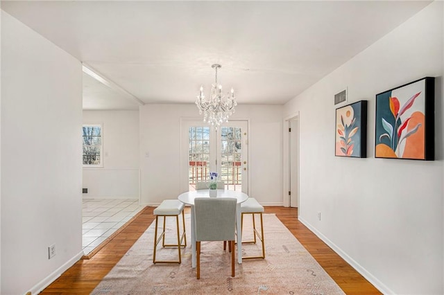 dining room with a notable chandelier, wood finished floors, visible vents, and a healthy amount of sunlight