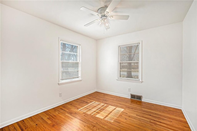 spare room featuring light wood-type flooring, visible vents, baseboards, and ceiling fan