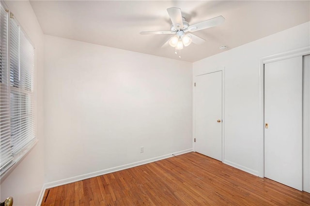 unfurnished bedroom with a closet, baseboards, wood finished floors, and a ceiling fan