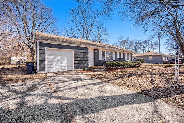 single story home with aphalt driveway, a chimney, and an attached garage