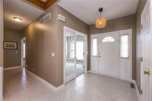 entryway featuring light tile patterned floors, visible vents, a textured ceiling, and baseboards