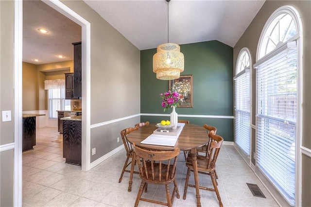 dining area featuring light tile patterned floors, visible vents, baseboards, and vaulted ceiling