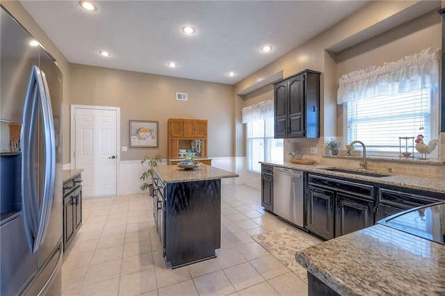 kitchen featuring visible vents, light tile patterned floors, light stone counters, stainless steel appliances, and a sink