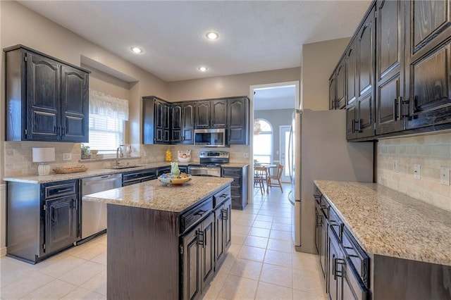 kitchen with a sink, stainless steel appliances, a healthy amount of sunlight, and light tile patterned flooring