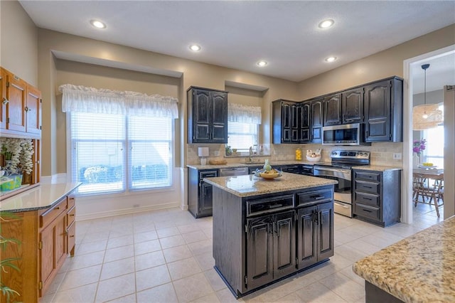 kitchen with a sink, backsplash, a center island, appliances with stainless steel finishes, and light tile patterned floors