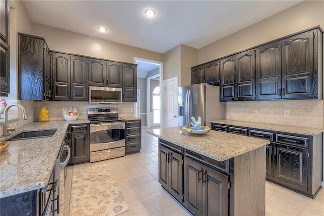 kitchen with decorative backsplash, light stone countertops, appliances with stainless steel finishes, and a sink