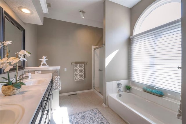 full bathroom featuring a sink, a shower stall, double vanity, baseboards, and a bath