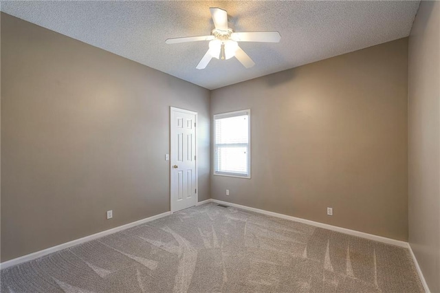 empty room with visible vents, baseboards, ceiling fan, light colored carpet, and a textured ceiling