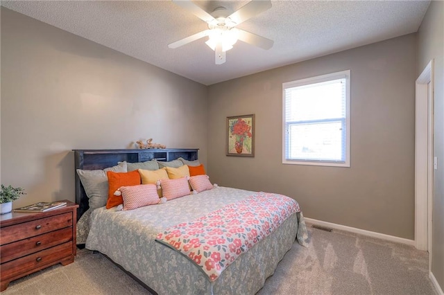 bedroom featuring baseboards, visible vents, ceiling fan, a textured ceiling, and light carpet