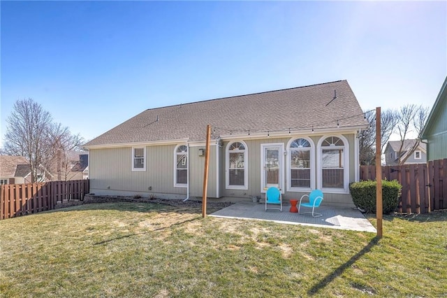 rear view of property featuring a yard, a patio, and a fenced backyard