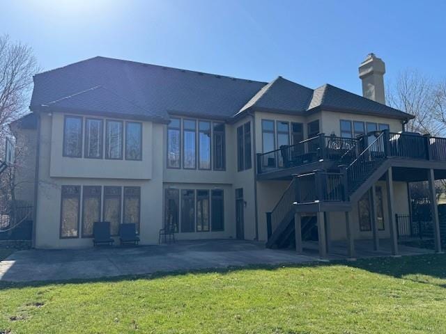 rear view of property featuring a wooden deck, a lawn, stairs, and a patio area