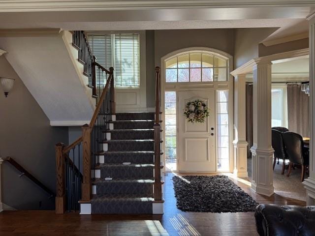 foyer entrance featuring stairway, ornamental molding, wood finished floors, and decorative columns