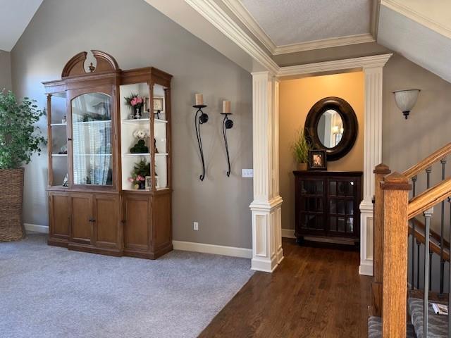 interior space with carpet, baseboards, ornamental molding, stairs, and vaulted ceiling