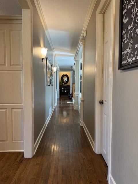 hallway with baseboards, wood finished floors, and crown molding