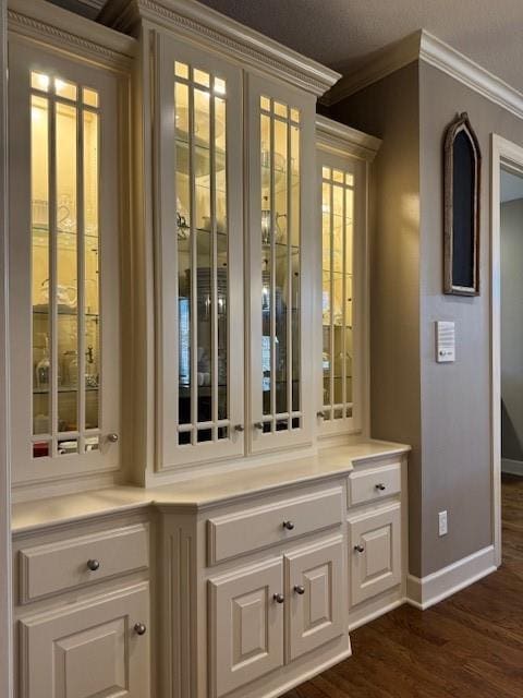 bar featuring dark wood-style floors, baseboards, and ornamental molding