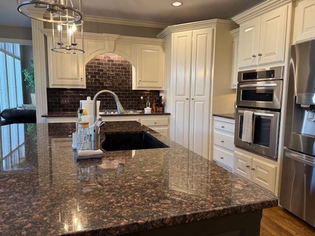 kitchen featuring a sink, stainless steel appliances, tasteful backsplash, and dark stone countertops