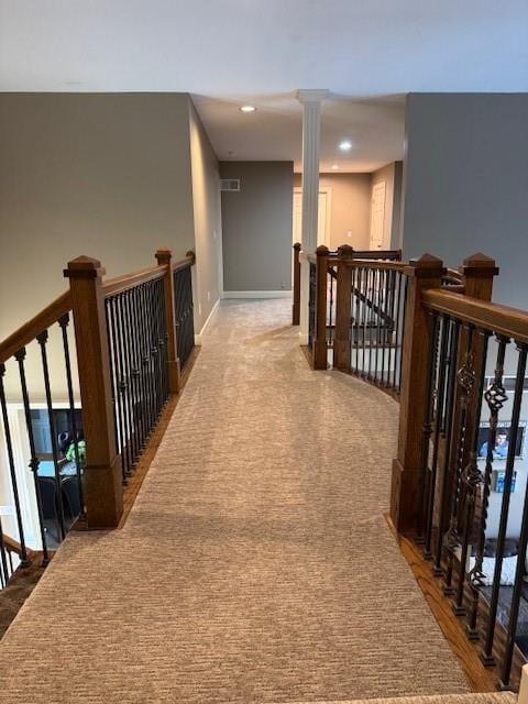 hall featuring recessed lighting, decorative columns, and an upstairs landing