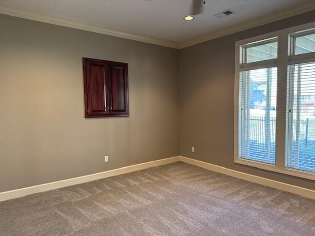 carpeted empty room featuring visible vents, baseboards, and ornamental molding