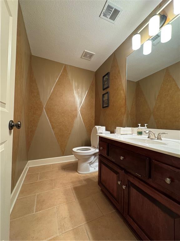 bathroom with visible vents, toilet, a textured ceiling, and vanity