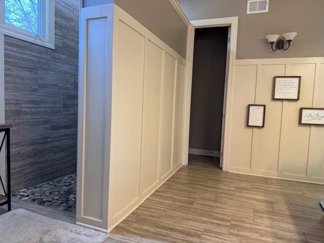 interior space featuring a decorative wall, wood finished floors, and visible vents