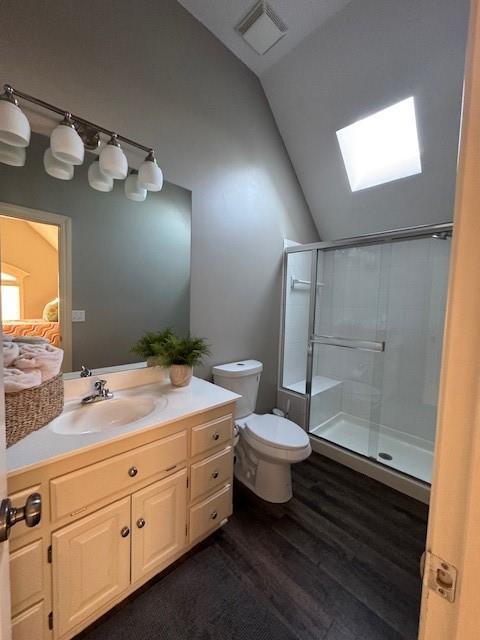 full bathroom with visible vents, a shower stall, toilet, vaulted ceiling, and wood finished floors