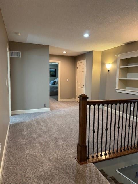 hall featuring visible vents, baseboards, recessed lighting, a textured ceiling, and carpet flooring