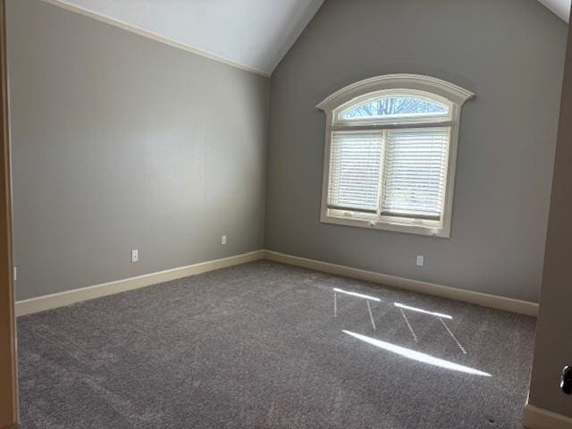 carpeted empty room featuring baseboards and vaulted ceiling