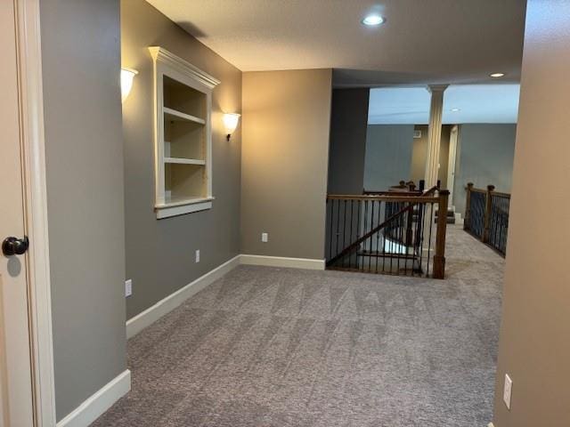 spare room with built in shelves, recessed lighting, carpet flooring, baseboards, and ornate columns