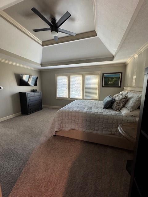 carpeted bedroom featuring ceiling fan, a tray ceiling, baseboards, and ornamental molding