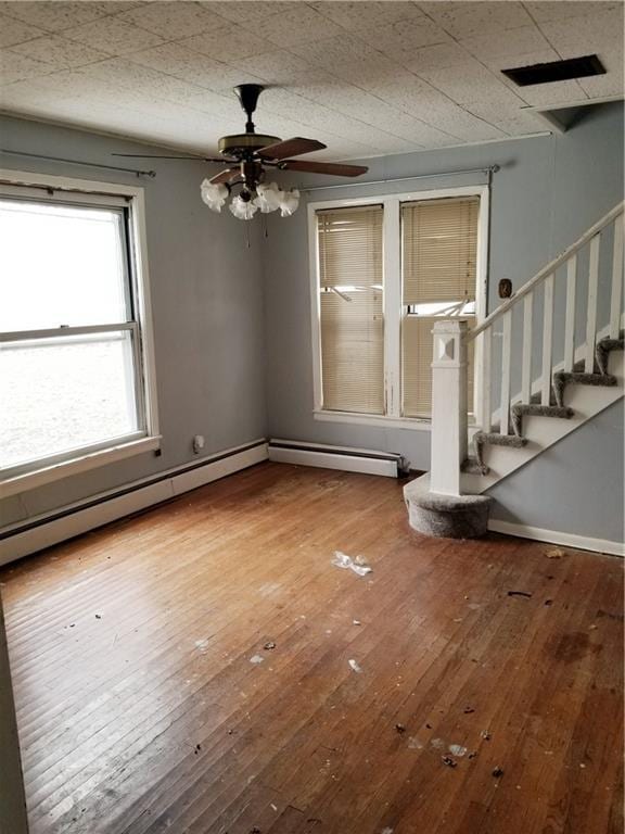 interior space with visible vents, wood-type flooring, baseboards, ceiling fan, and stairs