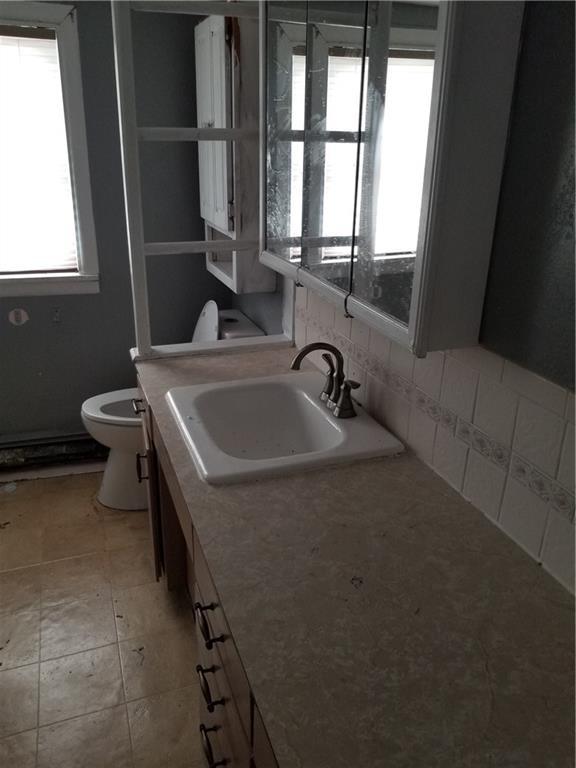 bathroom featuring a sink, decorative backsplash, and toilet