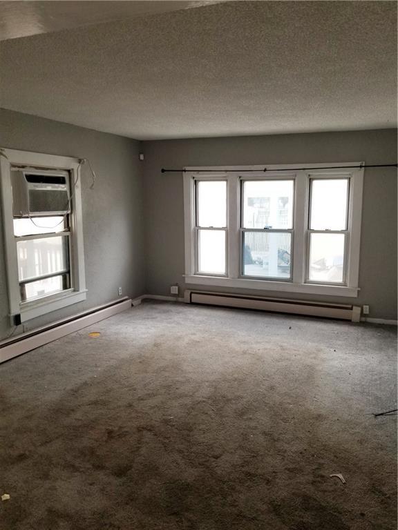 carpeted empty room featuring a baseboard heating unit, baseboards, baseboard heating, and a textured ceiling