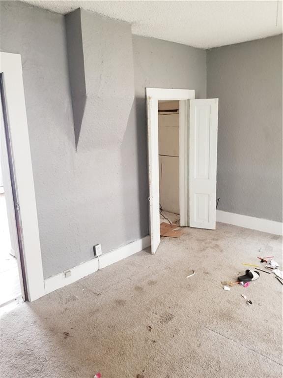 unfurnished bedroom featuring carpet flooring, a textured ceiling, and baseboards