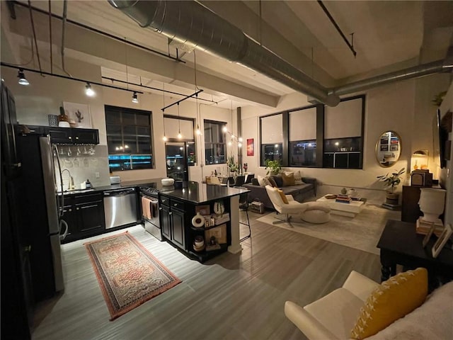 kitchen featuring dark cabinetry, dark countertops, a towering ceiling, and stainless steel appliances