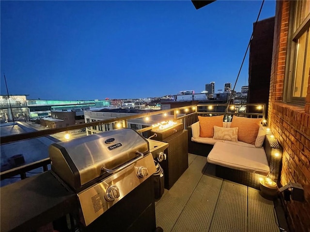 balcony at twilight with area for grilling, a grill, and a view of city lights