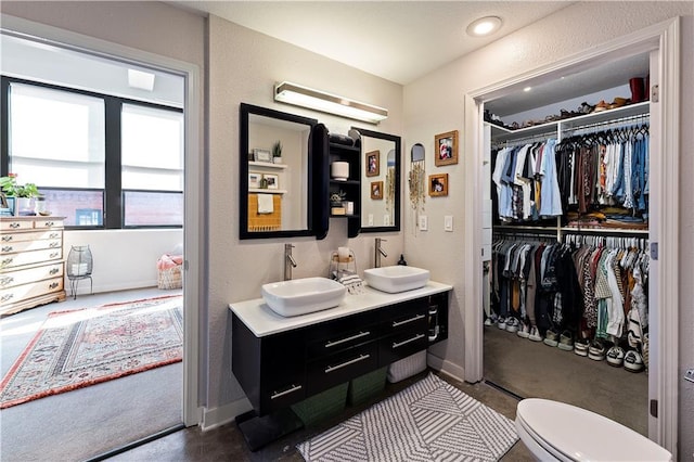 full bath with a sink, a spacious closet, double vanity, and a textured wall