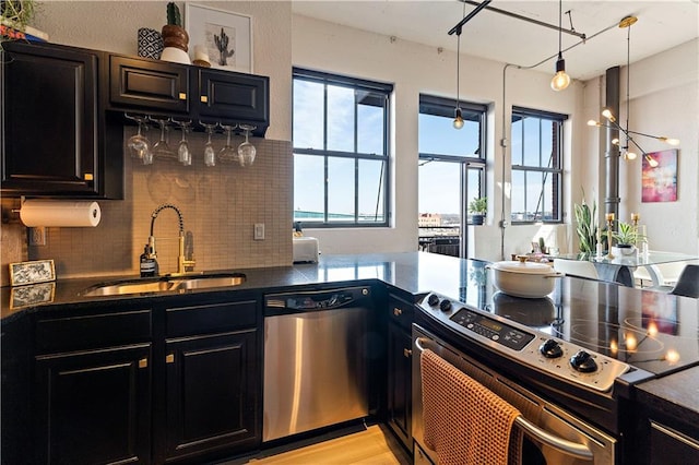 kitchen with a sink, decorative backsplash, stainless steel appliances, dark countertops, and dark cabinets