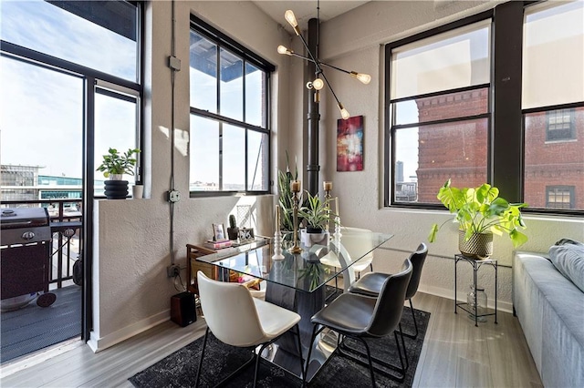 dining space featuring baseboards, wood finished floors, and a textured wall