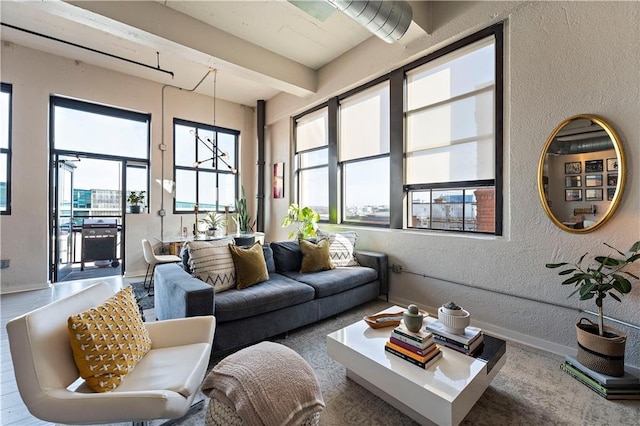 living area with beamed ceiling, baseboards, and a textured wall