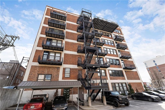 view of building exterior with stairway and covered and uncovered parking