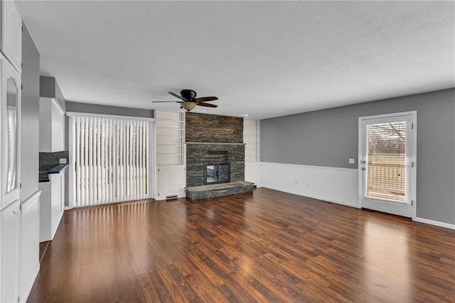 unfurnished living room featuring ceiling fan, built in features, dark wood-style floors, and a fireplace