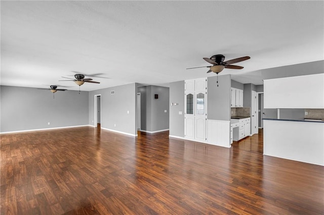 unfurnished living room featuring baseboards, dark wood-type flooring, and a ceiling fan