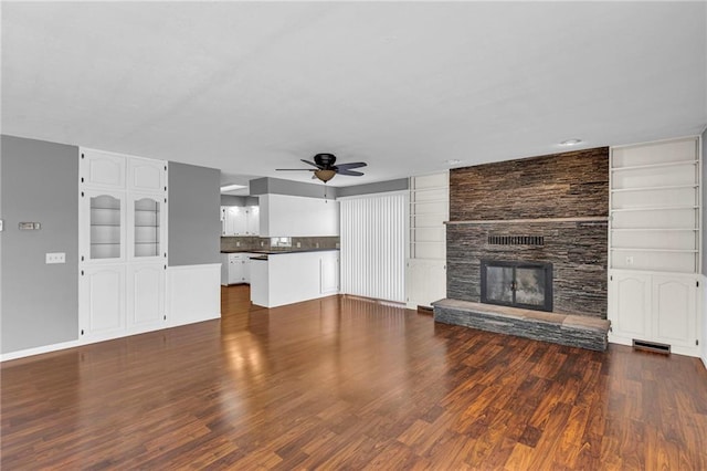 unfurnished living room with a ceiling fan, built in features, a fireplace, and dark wood-style flooring