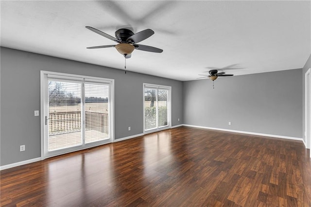 unfurnished room with dark wood-style floors, baseboards, and ceiling fan