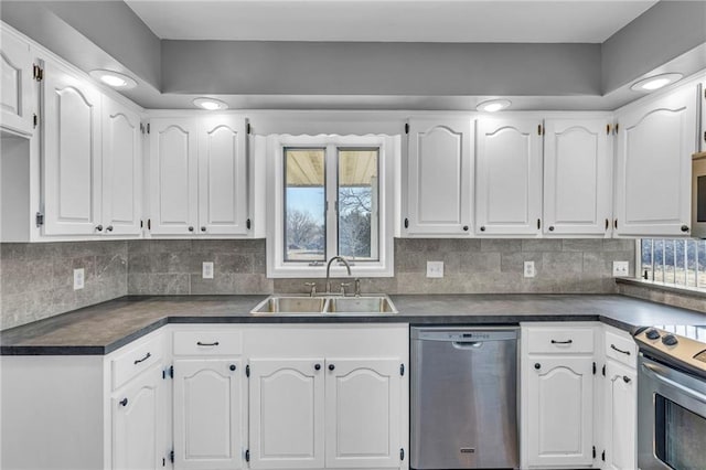 kitchen with dark countertops, appliances with stainless steel finishes, white cabinetry, and a sink