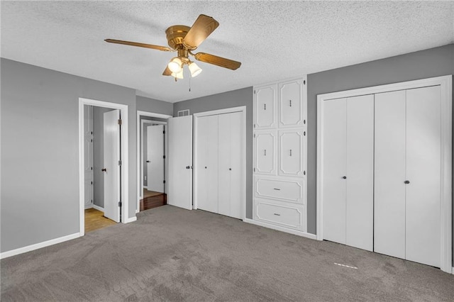 unfurnished bedroom featuring visible vents, a textured ceiling, two closets, and carpet floors